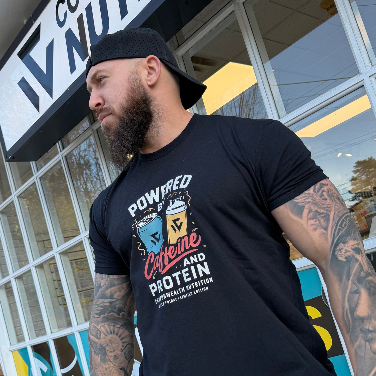 Man wearing a black t-shirt with graphic design in front of a store named 'Common Sense Nutrition'.