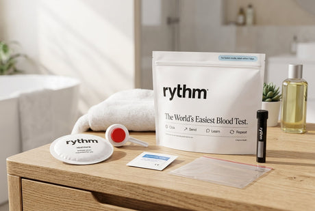 Rythm at-home blood test kit with collection device, heat pack, alcohol wipe and sample tube on a bathroom counter
