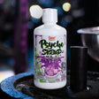 Bottle of Psycho Syrup Purple Drank on a dark surface with a blurred colorful background